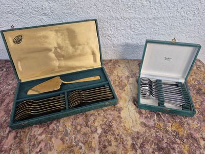 deux sets d'argenterie dans un coffret sur une table