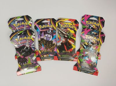 Trois paquets de cartes à collectionner Pokémon sont posés sur une table