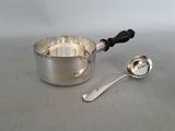 une casserole en argent et une cuillère posées sur une table
