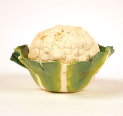 a white cauliflower in a green bowl on a white surface