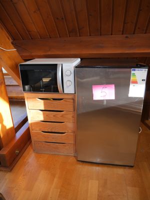 a silver refrigerator and a microwave in a small room