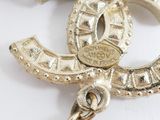 a white pearl and gold brooch on a white surface