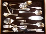 de nombreuses cuillères en argent et cuillères à soupe dans une boîte en bois