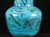 un vase bleu posé sur une surface noire