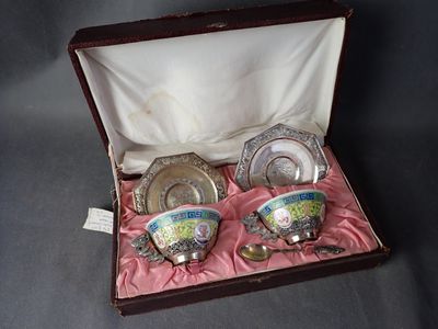 trois tasses et soucoupes dans une boîte posée sur une table