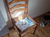 a wooden chair with a newspaper on it in the corner of a room