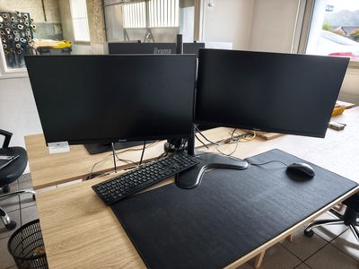 two computer monitors sitting on top of a wooden desk