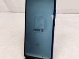 the back of a black phone with a blue screen sitting on top of a bed