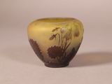 a yellow vase with flowers on it sitting on a table