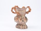 un petit vase avec un motif sur une surface blanche