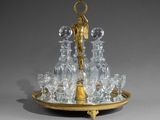 un plateau sur lequel se trouvent un verre et une assiette dorée, avec un bougeoir posé dessus