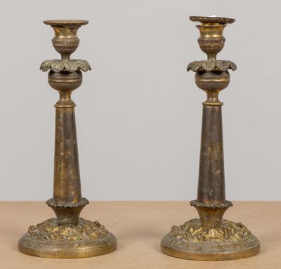une paire de bougeoirs anciens en laiton posés sur une table en bois