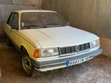 une petite voiture blanche garée dans un garage, à côté d'un pneu
