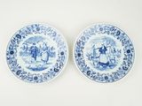 deux assiettes bleues et blanches sur lesquelles figurent des personnages, posées sur une table