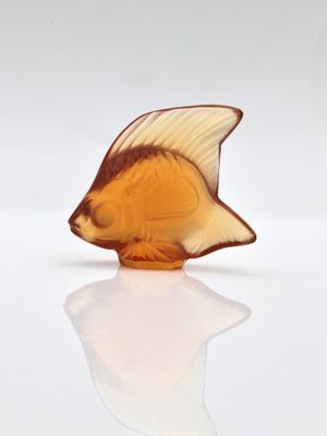 a glass figurine of a fish on a white surface