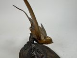 bronze statue of a bird on a rock with a bird on it