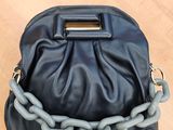 un sac à main noir et gris, entouré d'une chaîne, posé sur une table en bois