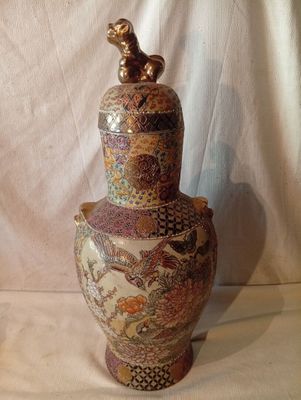 un vase surmonté d'un oiseau, posé sur une table