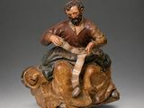 statue of a man sitting on top of a wooden animal