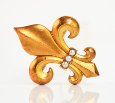 une photo en gros plan d'une broche en or ornée de perles