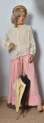 un mannequin représentant une femme avec un chapeau et un parapluie