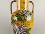 un vase jaune orné de fleurs peintes, posé sur une table