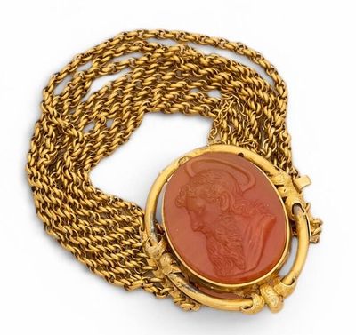 a close up of a gold necklace with a red stone in the center