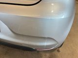 the rear end of a white car with a denting bumper
