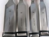 six knives are lined up on a table with a red handle