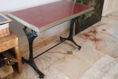 a small table with a red top sitting on a marble floor