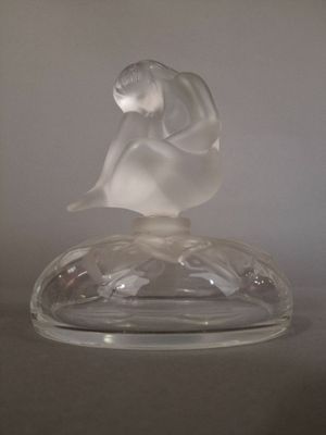 une figurine en verre représentant une femme assise sur un plateau en verre