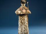 statue of a woman holding a stick in her right hand and a hat on her head