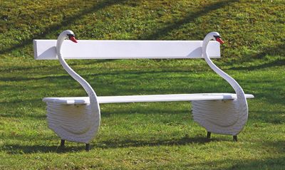un banc blanc sur lequel sont posés deux cygnes, dans l'herbe