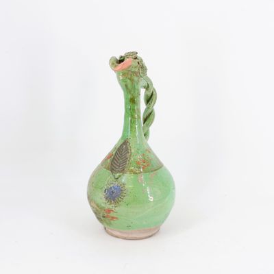 un vieux vase vert posé sur une table blanche