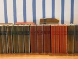 several old books are lined up on a shelf in front of a striped wall