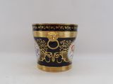 a close up of a black and gold cup on a white surface