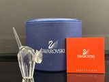 une figurine en cristal représentant un cheval, posée sur une table à côté d'une boîte de Swarovski
