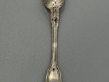 silver spoon on a gray surface with a small spoon sticking out of it