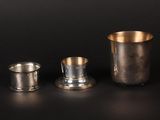 three silver cups and a silver cup on a black table