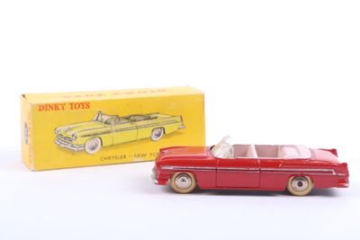 a red toy car next to a yellow box on a white surface