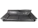 un canapé en cuir noir posé sur un sol blanc