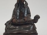 statue représentant un homme assis sur une chaise, avec un chat sur les genoux