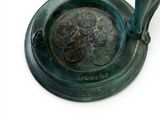 a green metal ashtray with a flower design on it