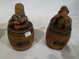 pair of ceramic figurines of a woman and a man sitting in a barrel