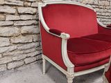 a red chair and a white chair in front of a stone wall