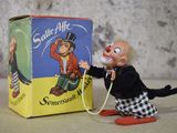 un clown en peluche tenant un tuyau d'arrosage devant une boîte