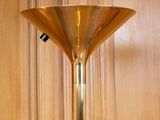 a tall gold lamp that is on top of a table
