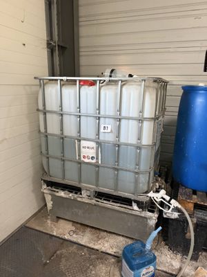 a large container with a water hose next to a blue barrel