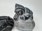 a statue of a cat sitting on a rock next to a hand