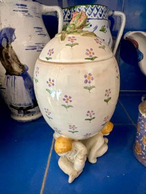 un grand vase blanc orné d'un oiseau, posé sur un comptoir bleu